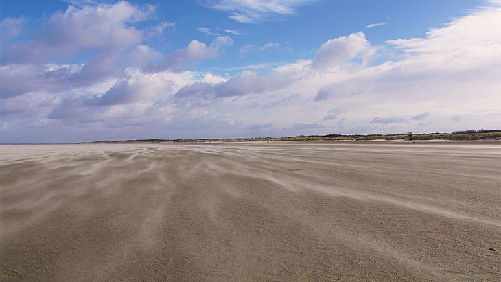 Der Wind zaubert Muster auf den Sand am Strand